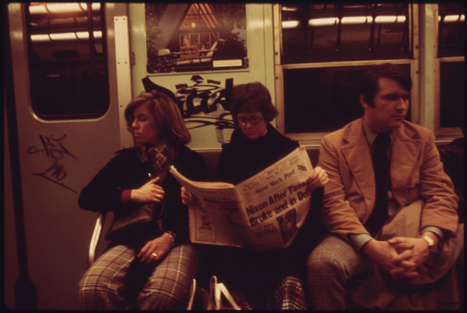 Passengers on a New York City subway car in 1974, one reading a newspaper with a Nixon headline on the front page